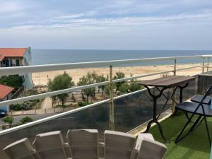 a balcony with chairs and a table and the beach at Face Mer 2 chambres parking in Hossegor