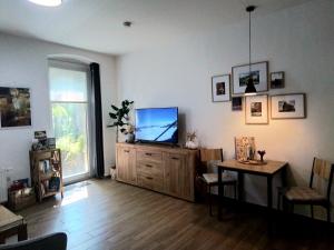 ein Wohnzimmer mit einem Flachbildfernseher auf einem Holzschrank in der Unterkunft Johnis FeWo, Nähe Stadtzentrum - Uni in sehr ruhiger Lage mit Terrasse und eigenem Parkplatz in Cottbus
