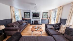 a living room with couches and a table at Large country house with garden, outdoor spa area & games room with Hot Tub and Fire Pit in Wigtown
