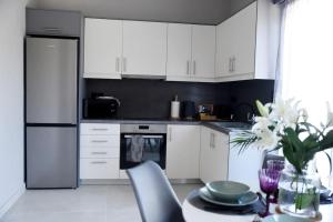 a kitchen with white cabinets and a table with a vase of flowers at Olivea's House in Corfu