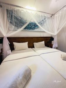 two white beds in a room with a painting on the wall at Villa Maria in Bentota