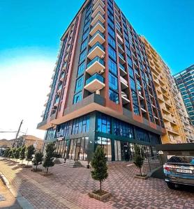 een hoog gebouw met een auto ervoor geparkeerd bij Angisa 72 Sea star in Batoemi