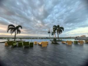a patio with chairs and tables and palm trees at The Mactan Newtown Boulevard Studio in Punta Engaño