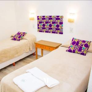 ein Zimmer mit zwei Betten und einem Tisch in der Unterkunft HotelMora in Puerto Madryn