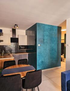 eine Küche mit einem Tisch und einer blauen Wand in der Unterkunft Kryształ A10, Garaż in Karpacz