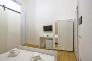 una stanza bianca con un letto e una scrivania di Elegante matrimoniale clemente house catania centro a Catania