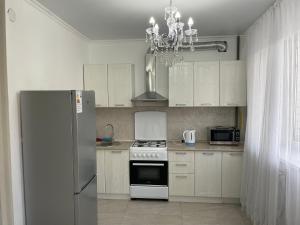 a kitchen with white cabinets and a refrigerator at Уютная квартира-студия в Атырау ЖК MODERN SITY in Atyraū