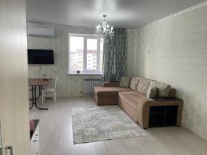 a living room with a couch and a table at Уютная квартира-студия в Атырау ЖК MODERN SITY in Atyraū