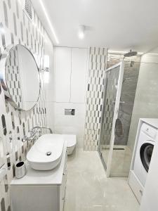 a white bathroom with a sink and a washing machine at Apartament Zielona Ochota in Warsaw