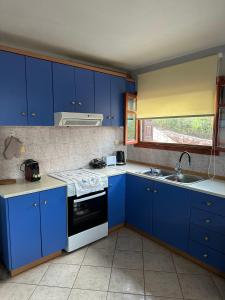een keuken met blauwe kasten en een wastafel bij Alice Apartment in Ayia Evfimia