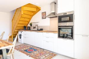 Appartement à 200 m de la plage في ميميزان: مطبخ بدولاب بيضاء ودرج +صورتان