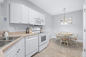 a kitchen with white cabinets and a dining room table at The Havens Barefoot Resort Unit 727 in North Myrtle Beach