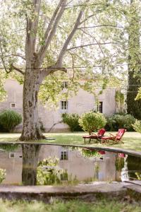 two red chairs and a tree in front of a house at Château La Bruguière in Tornac
