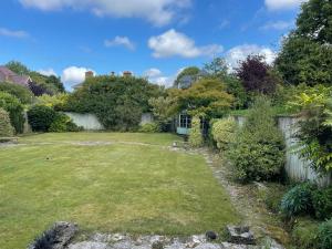 a yard with a fence and a grass yard at Charming Bournemouth house with beautiful spacious gardens, 5 min drive to beaches, free parking for 2-3 cars in Bournemouth