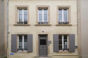 budynek z czterema oknami i drzwiami w obiekcie Appartements du Port w mieście Port-en-Bessin-Huppain