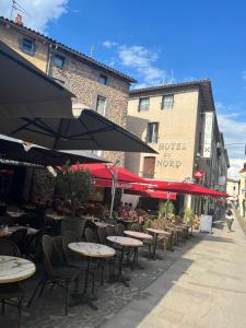 an outdoor cafe with tables and chairs and umbrellas at Hotel du Nord - Ville-Haute in Saint-Flour