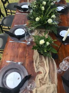 una mesa de madera cubierta con platos y jarrones con flores en Lotties, en Kampala