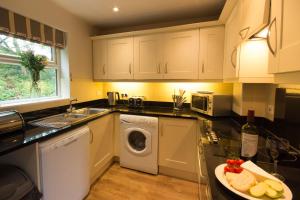 a kitchen with white cabinets and a sink and a dishwasher at Farley in Matlock
