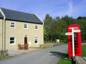 a red telephone booth in front of a house at Farley in Matlock