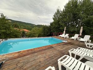 ein Swimmingpool auf einer Holzterrasse mit weißen Stühlen in der Unterkunft Casa Daria in Ormindea