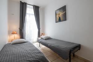 two twin beds in a room with a window at "Le Zen" by EnjoyNice, central spacious apartment with Airco, beach at 10 min in Nice