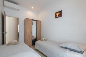 two beds in a room with white walls at "Le Zen" by EnjoyNice, central spacious apartment with Airco, beach at 10 min in Nice