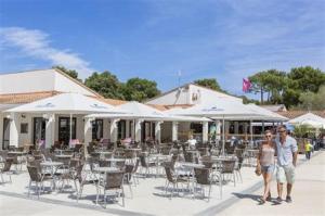 two people standing in front of a patio with tables and chairs at Mobil Home 10 personnes Camping la Tremblade Emplacement 074 in La Tremblade