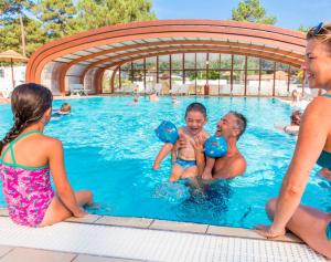 a man and two children playing in a swimming pool at Mobil Home 10 personnes Camping la Tremblade Emplacement 074 in La Tremblade +9 photos