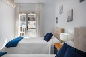 a bedroom with a bed with blue pillows and a window at Encantadora casa en el Casco Antiguo de Marbella in Marbella
