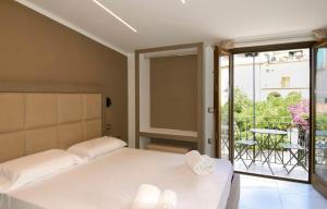 a bedroom with a bed and a balcony at Belmà Aparthotel and Rooms in Marina di Camerota