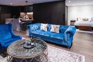 a living room with a blue couch and a table at Luxury Melbourne CBD Apt in Iconic QT Building in Melbourne