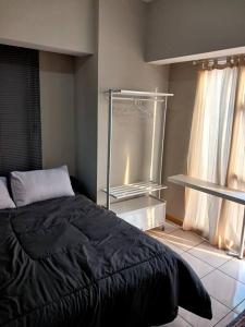 ein Schlafzimmer mit einem schwarzen Bett und einem Fenster in der Unterkunft M Town Residence Apartment Serpong 1 Bedroom in Pumpangsineng