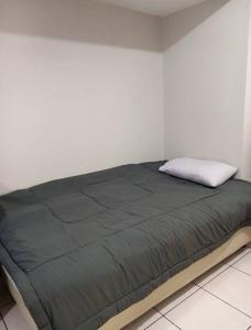 ein Bett mit einer schwarzen Decke und einer weißen Wand in der Unterkunft M Town Residence Apartment Serpong 1 Bedroom in Pumpangsineng