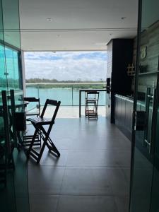 リオデジャネイロにあるPousada Seven Sunset Club Marambaiaの水辺の景色が見える椅子とテーブルのある部屋