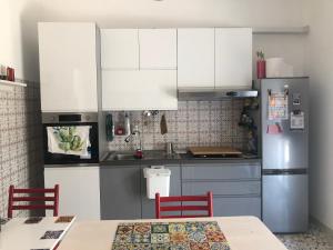 a kitchen with white cabinets and a stainless steel refrigerator at Casa Renjinella Torre Suda in Torre Suda