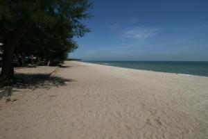 a sandy beach with trees and the ocean at Beachfront Hotel Cha Am in Cha Am