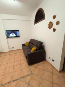 a living room with a brown couch and a flat screen tv at Le perle 2 di Naxos in Giardini Naxos