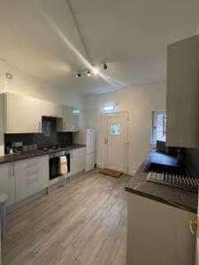 a kitchen with white cabinets and a wooden floor at 2 Bedrooms Holiday home in Edinburgh near City Center in Edinburgh