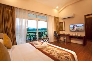 a hotel room with a bed and a large window at Resort De Coracao - Corbett , Uttarakhand in Rāmnagar