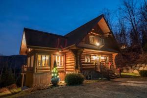 a log cabin with a christmas tree in front of it at Héritage Nature Scandinavian Chalet Spa & View in Sainte-Adèle