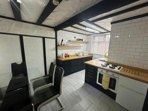 a kitchen with black cabinets and a table and chairs at Modern Pink Cottage in Blackpool in Blackpool