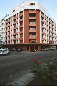 un grand bâtiment avec des voitures garées dans un parking dans l'établissement Royal Court Hotel, à Mombasa