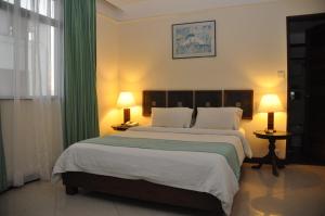 a bedroom with a large bed with green curtains at Royal Court Hotel in Mombasa