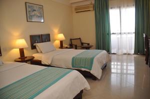 a hotel room with two beds with green curtains at Royal Court Hotel in Mombasa