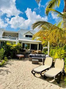 una casa con due sedie e un divano sulla spiaggia di Palm Beach House - Stunning 3 Bedrooms beachfront - Nettle Bay Beach Club a Baie Nettle