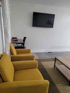 a living room with a yellow couch and a tv at Renovated 2 Bed Walltown Home Walk To Duke! B in Durham