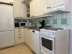 a kitchen with white appliances and white cabinets at Fredrik Kaksio Haminassa in Hamina