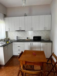 a kitchen with a wooden table and white cabinets at Emilios house in Dhërmi +41 photos