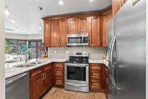 eine Küche mit Holzschränken und einem Edelstahlkühlschrank in der Unterkunft 1BR Deer Valley Condo-On FREE Shuttle Line in Park City