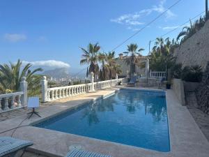 una piscina con una valla blanca y palmeras en Villa Cost-a Blanca, en Benissa